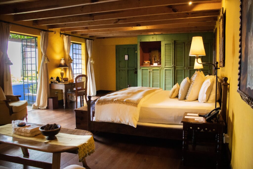 Habitación de lujo de Casa Palopó con decoración colonial en tonos amarillos y verdes, hotel guatemalteco distinguido por la Guía Michelin