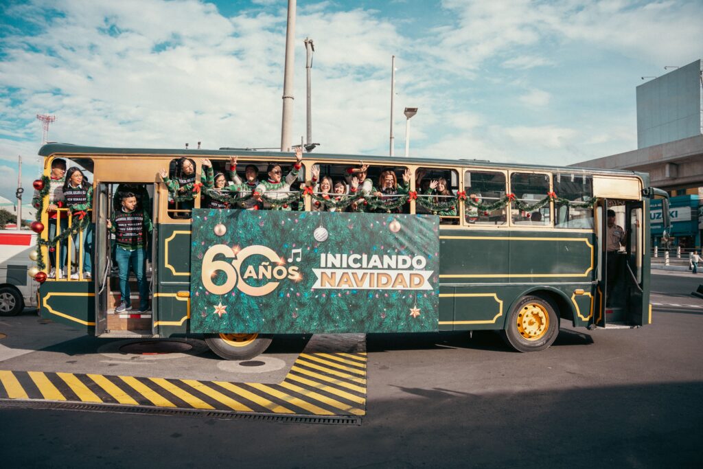 Equipo de B&B celebra los 60 años del jingle navideño en un bus decorado con la leyenda '60 años Iniciando Navidad