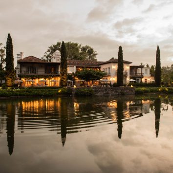Vista al atardecer de Villa Bokéh, hotel guatemalteco distinguido por la Guía Michelin, con su fachada colonial reflejada en el lago